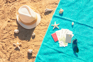 Hat, money, passport, credit card and sunglasses on towel on sand beach. Top view.