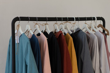 Minimalistic rack with linen colourful clothes on white studio background.