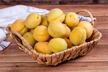 Obraz na płótnie Canvas Apricots on wood background. A pile of fresh apricots in a basket. close up