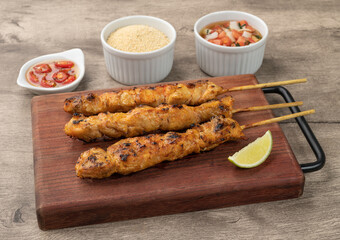 Chicken skewers over wooden board with farofa and vinaigrette