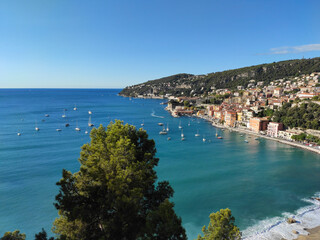 Fototapeta na wymiar View of Port Villefranche-Santé with boats, catamarans, sails boats, speed boats, and yachts moored to the pier, during daytime with a clear blue sky, Villefranche-sur-Mer, France.