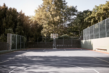 An empty still life of a basketball court on a sunny day with white marking with a hoop and net. A...