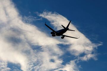 Naklejka na ściany i meble Flight of the plane on the background of a beautiful cloudy sky.