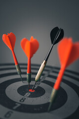 Close up shot of the dart arrow hit on bulleyes of dartboard to represent that the business reached the target of company with dark tone picture style. Target and goal as concept. 