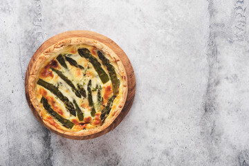 Obraz na płótnie Canvas Quiche. Homemade asparagus pie or quiche with cheese, pecorino, bacon and spinach on gray concrete light table background. Asparagus and cheese tart. French Quiche. Top view.