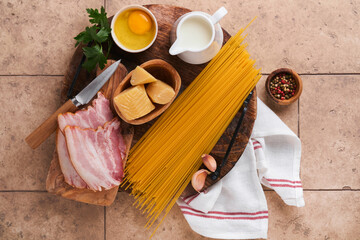 Ingredients for Pasta Carbonara. Traidtional Italian Pasta Carbonara Ingredients bacon, spaghetti, parmesan and egg yolk, garlic. Beige old tile table background. Top view. Copy space