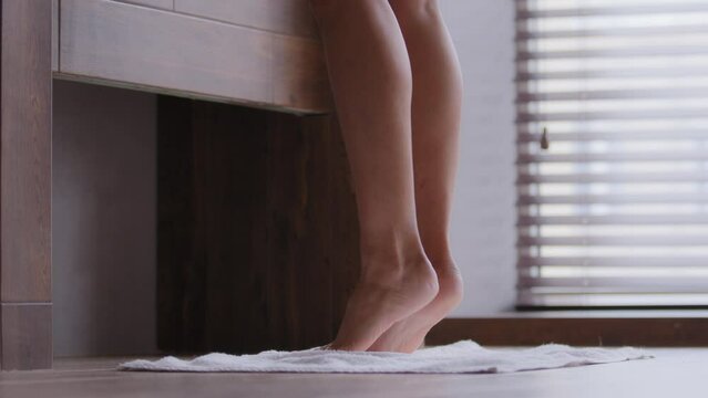 Close-up of slim bare legs and feet young unrecognizable woman walking in bathroom attractive female legs stand on tiptoe enjoying daily morning routine alone hygiene procedure girl doing leg exercise