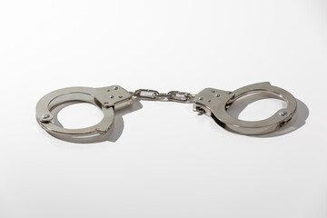 Police handcuffs isolated on white background with light shadows.