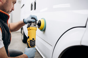 Car detailing - Hands with orbital polisher in auto repair shop. Selective focus.