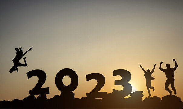 Silhouette of a jumping person with the numbers 2023 on the mountain at sunset against the background of morning sunlight.