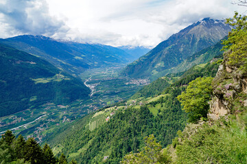 a hiking trail overlooking the alpine valley of the city Merano surrounded by the Texel group mountains (Oetztaler Alpen in Südtirol, South Tyrol, Italy)