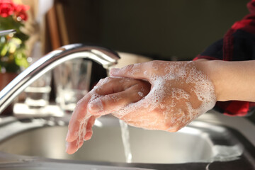 Woman washing hands in kitchen, closeup view