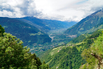 a hiking trail overlooking the alpine valley of the city Merano surrounded by the Texel group mountains (Oetztaler Alpen in Südtirol, South Tyrol, Italy)	