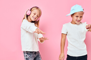 a boy in a cap and a girl standing side by side posing fashion pink color background