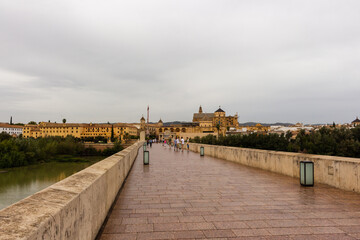 Fototapeta premium Cordoba, Spain, September 13, 2021: Guadalquivir River and the Roman Bridge, with Cordoba Mosque-Cathedral in the background.