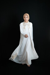 Fototapeta na wymiar Muslim woman wearing white abaya isolated on black background
