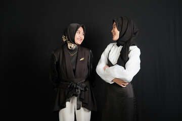 Two happy young Asian Muslim women isolated on black background.