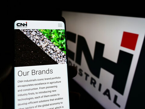 Stuttgart, Germany - 01-29-2022: Person holding cellphone with webpage of heavy equipment company CNH Industrial N.V. on screen in front of logo. Focus on center of phone display.