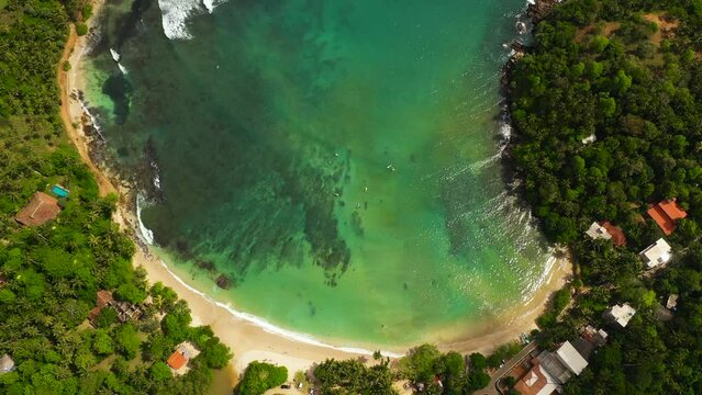 Travel concept: flying over a beautiful sandy beach and a blue ocean. Hiriketiya, Sri Lanka.