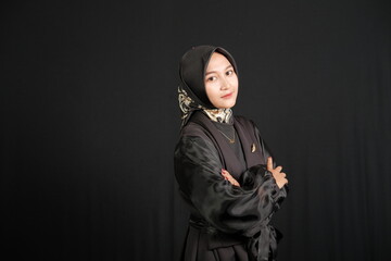 Portrait of Indonesian woman wearing hijab folding her hands, isolated on black background