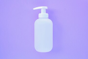 White unbranded plastic dispenser pump bottle on violet background with copy space for text. Cosmetic package mockup, liquid soap flacon, hand sanitizer without label, shampoo organic spa, shower gel