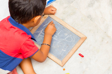 a baby child writing on a graphite slate.