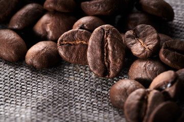 Roasted coffee beans decorated with burlap fabric close up creative background