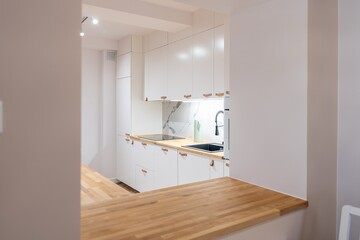 Modern white kitchen in an apartment. Wooden floor