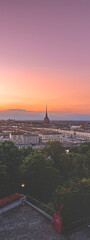 Obraz premium Turin, Italy. Panoramic view of the city in the evening after sunset. Skyline with the Mole in the evening. Banner vertical. July 1, 2022.