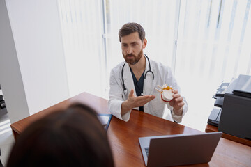 Male professional doctor consults patient and shows the model of several spines in modern clinic