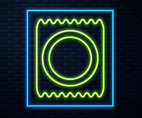 Fototapeta na wymiar Glowing neon line Condom in package icon isolated on brick wall background. Safe love symbol. Contraceptive method for male. Vector