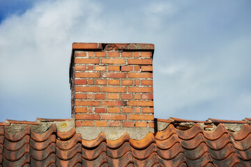An orange bricked roof with chimney against the blue sky with copy space on a sunny day. A brick...