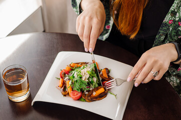Female client of the rastaurant is eating a salad. Close up