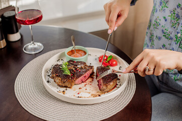 Woman client of the restaurant is eating a medium rare steak. Close up