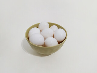 Many eggs, a bowl full of white eggs on a white background