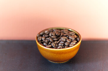 roasted coffee beans in a brown ceramic bowl on a dark table with space for text