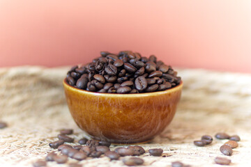 roasted coffee beans in a brown ceramic bowl on a table in natural design with space for text