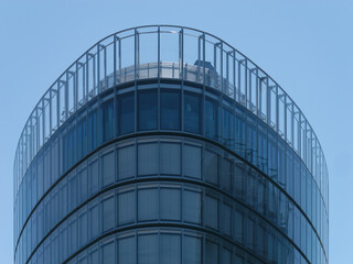 Close-up view of the top of a modern business tower with windows and a clear blue sky in the background