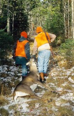 A pair of hunters work to get a buck out of the woods