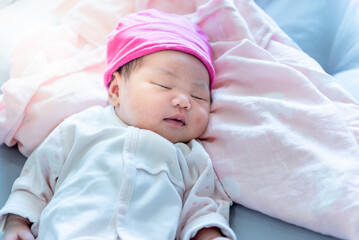 Baby newborn Asian girl, is 7 days old, Which has pink skin, are lying and sleeping on bed, to baby newborn and child concept.