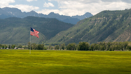 Large American flag gallantly flying over a pasture high in the San Jaun Mountains of Colorado; concepts of American and patriotism