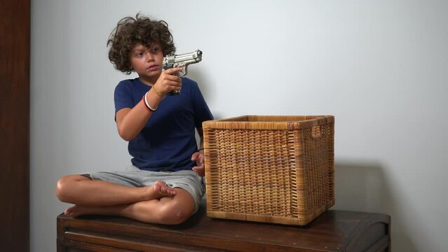 8-year-old boy alone at home finds a real gun in his parents' drawer - in America more and more children find guns in domestic places - social danger and violence