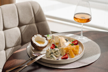 A dish with variety of cheese with honey and fruits on the table at the restaurant
