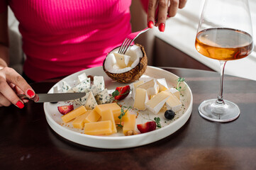 Female customer eating a dish with assortment of cheese at the restaurant. Close up