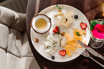 A dish with variety of cheese with honey and fruits on the table at the restaurant