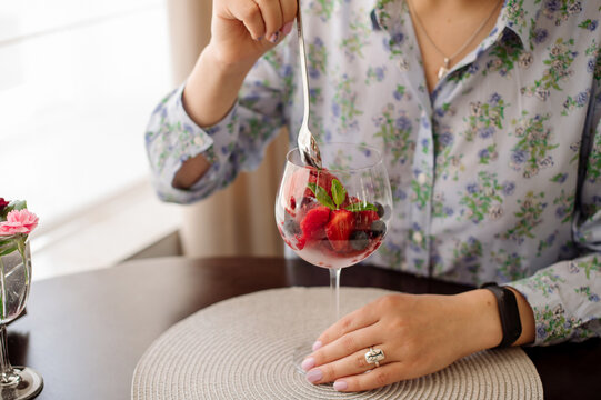 Female rastaurant client is eating a cold iced strawberry sorbet