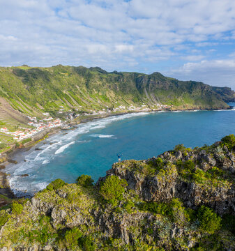 Aerial view of houses along the coastline with terrace fields on the slopes of the cliff overlooking the ocean, Santo Espirito, Azores, Portugal.