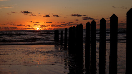 Colorful daybreak at the beach on North Padre Island; pylons to keep vehicles off the beach