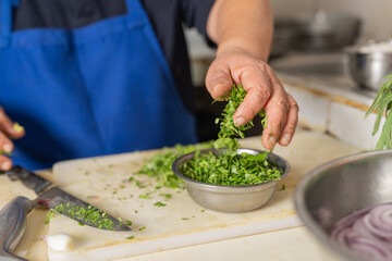 Cook preparing a bowl of chopped coriander for a ceviche dish in a restaurant