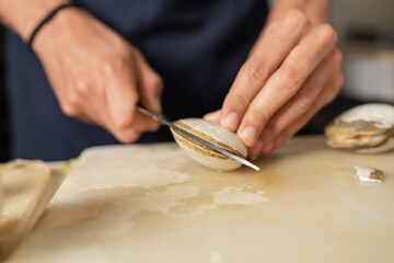 Cook opening a clam with a kitchen tool